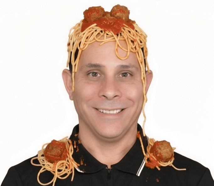 John grinning with cooked spaghetti draped over his head and shoulders
